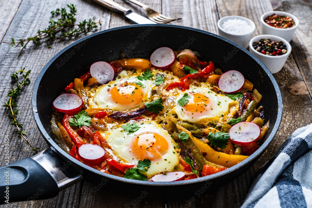 Shakshuka - fried eggs with vegetables in frying pan
