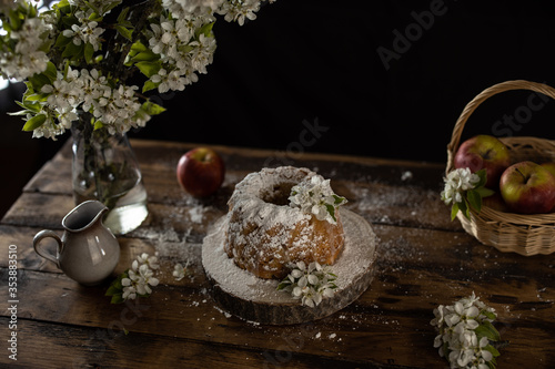 Rustic style apple bundt cake with powdered sugar on old wooden table