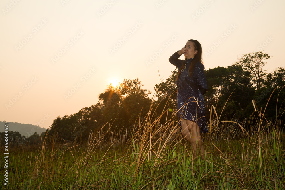 Fototapeta premium Portrait of Asian woman standing in grass field of forest Evening