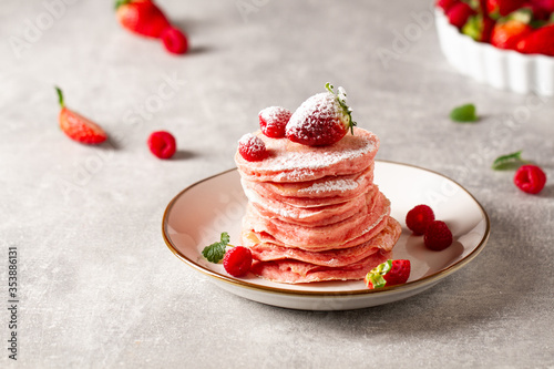 Stack of pink pancakes with strawberry. Pink colourful pancakes with berries. Breakfast