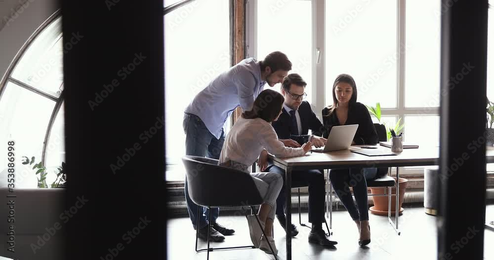 Diverse busy professional office team people working together looking at computer screen searching digital strategy solutions, analyzing data at group meeting room table. Corporate teamwork concept.