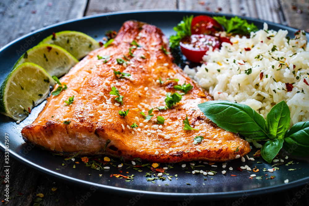 Fried salmon steak with rice and vegetables on wooden table
Fried salmon steak with rice and vegetables on wooden table