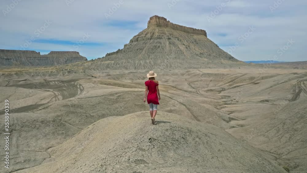 girl stands on a cliff of sandy mountains among the yellow dunes and looks into the distance in a winding landscape of rocky terrain girl stands on a cliff of sandy mountains among the yellow dunes and looks into the distance in a winding landscape of rocky terrain