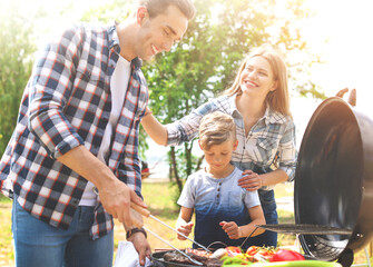 Happy family having barbecue with modern grill outdoors on sunny day