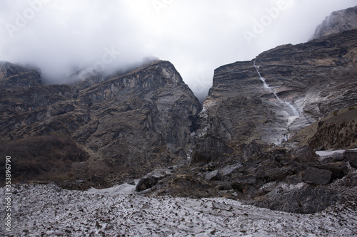 Fog and Clouds on Mountain Peaks with Waterfall and Snow