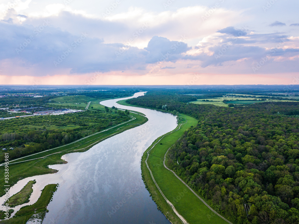 Aerial view on the river surrounded by forests with cloudy sky on the background