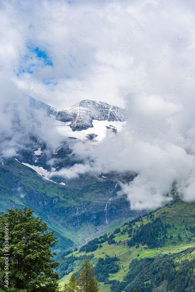 Snow covering the top of the mountain in Austrian Alps and green forest at the bottom