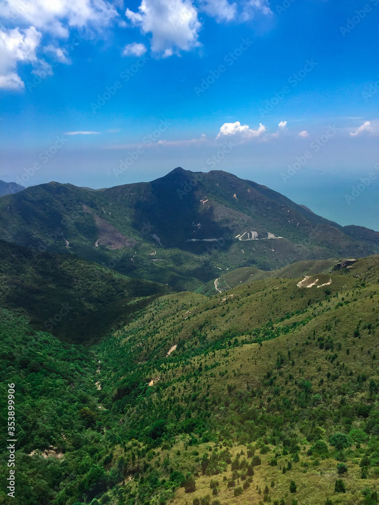 Green mountain scenery, with a sea behind and gentle clouds. Gives a feeling of freshness, a famous and popular travel place in Hong Kong. Above ground shots.