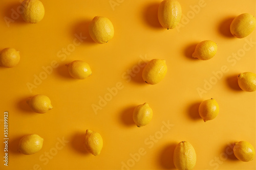 Top view of appetizing fresh lemons on yellow background. Citrus fruit possesses various health benefits, consumed by people to boost immune system. Ingredient for juice or dishes. Citrons indoor