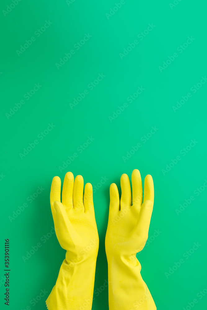 Women hands wearing a pair of yellow protective gloves on green background Women hands wearing a pair of yellow protective gloves on green background