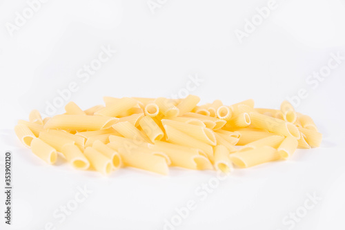 Raw penne pasta on a white background