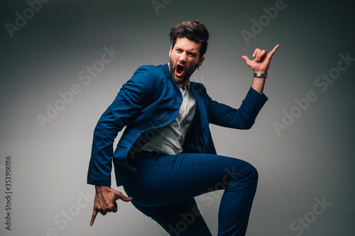 Happy young businessman jumping in the air on a gray background.