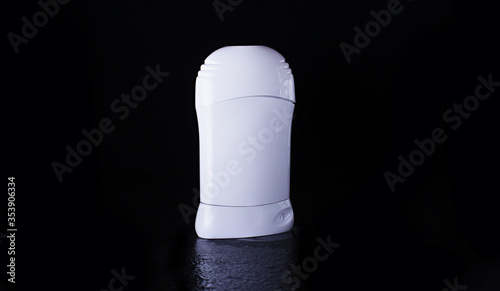 Dry deodorant in a white bottle on a black background with reflection below. Advertising photo of antiperspirant. Mock up deodorant..