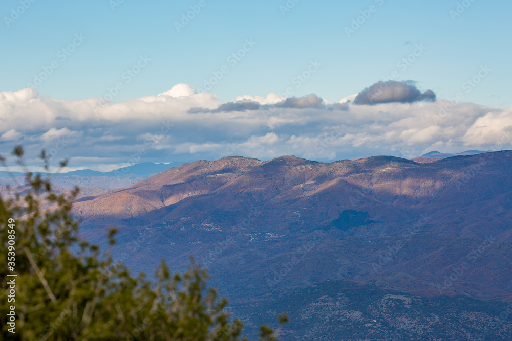 Sky with beautiful puffy white clouds and picturesque mountains, late autumn day in Northern Greece, Xanthi region, high angle colorful naturalistic view