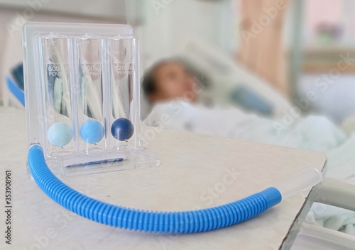Triflow incentive spirometer for patients.Triflow or Tri-ball on table.Selective focus with Female patients lie on the bed.Blur background.