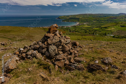 Carnlough viewed from the surrounding hills with a small stone cairn © stevie