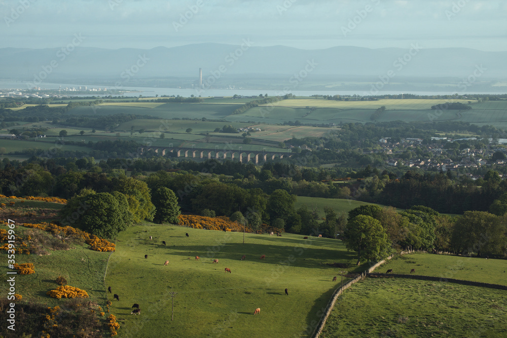 Top view of a rural Scottish landscape with villages, grazing cows, a stone bridge, sea and mountains. Avon Viaduct, Linlithgow and Gangemouth. Scotland