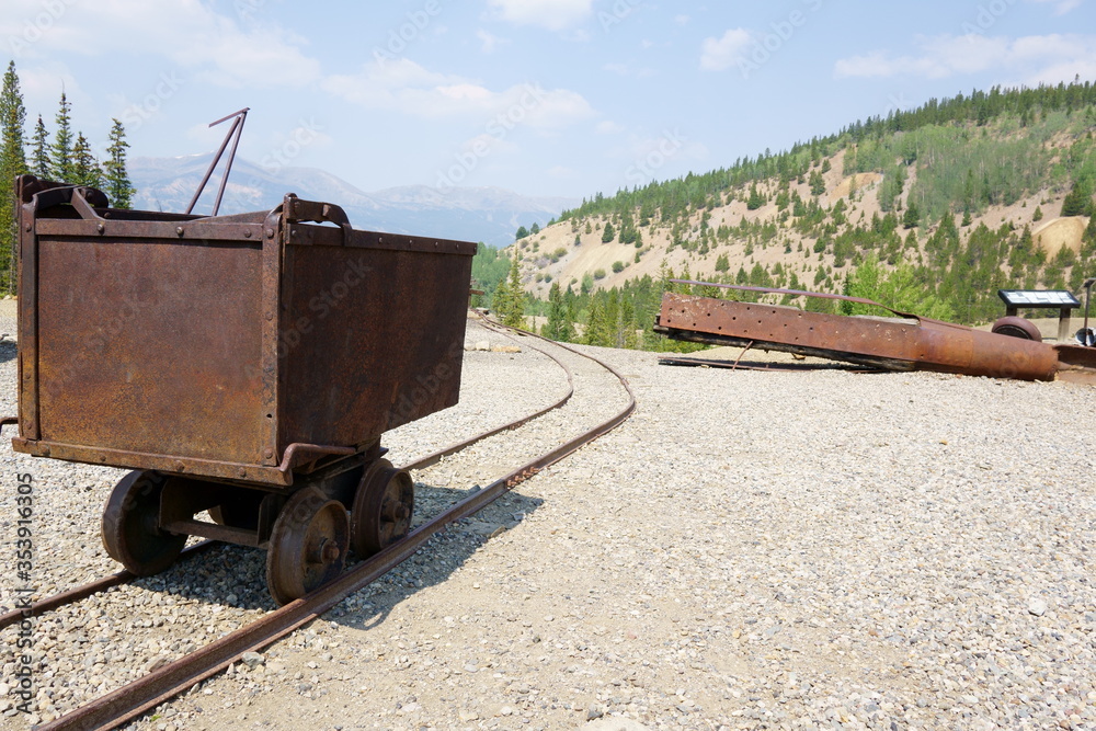 Steel ore cart sits on a railing outside of the mine Stock Photo