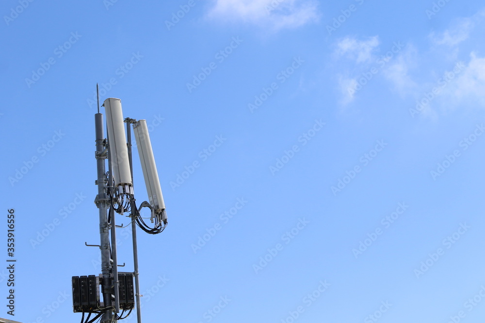 Cellular, mobile phone transmitter tower with blue sky and clouds middle