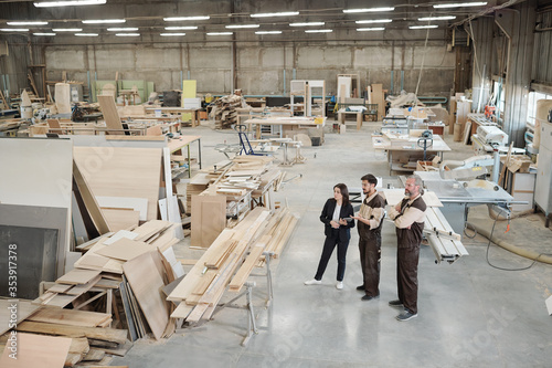 Young worker of furniture factory showing new equipment to female manager