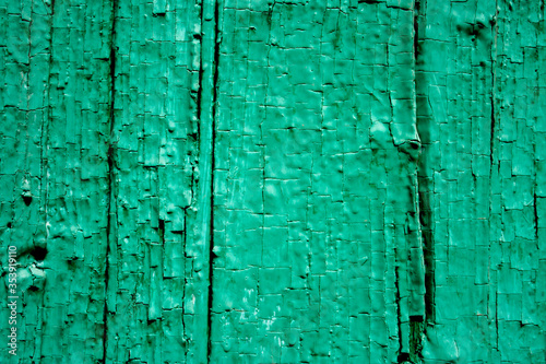 The natural surface, of painted vertical boards. The surface of the old wooden facing wall of the house. Cracked paint covers the texture of wooden boards.