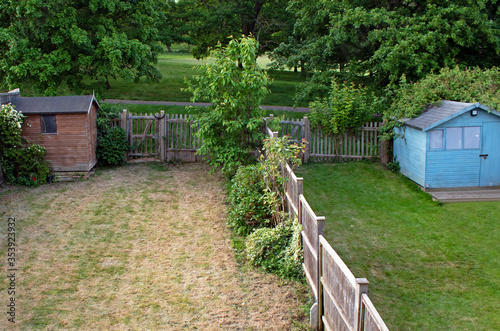 The grass is always greener on the other side - two neighboring gardens, one with fresh and lush green grass, the other with dried out yellow grass
