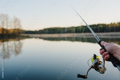 Fishing. Fisherman with rod, spinning reel on the river bank. Fishing for pike, perch, carp. Fog against the backdrop of lake. background Misty morning. wild nature. Article about fishing day.