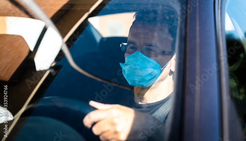 Man wearing protective mask driving. Man in protective mask driving a car in the city.