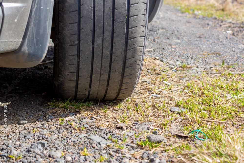 Shabby rubber tire of car wheel on gravel road during a summer trip Shabby rubber tire of car wheel on gravel road during a summer trip
