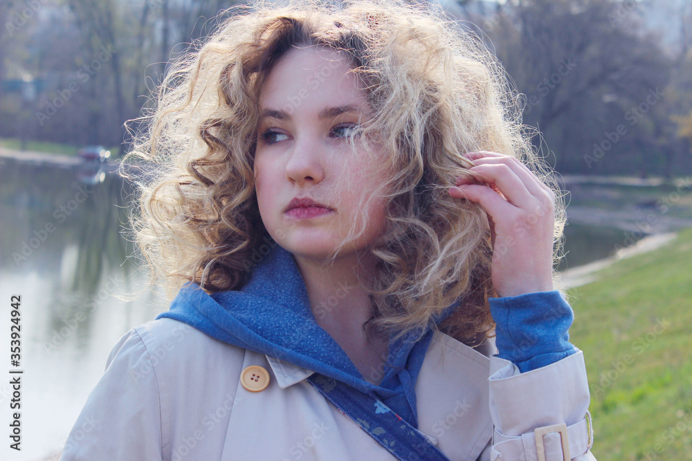 Naklejka premium Close up portrait of a youg girl looking to the side. Cute curly girl outdoor. People, travel, nature concept.