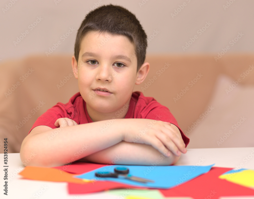 Cute smiling boy is cutting paper using scissors. Education, school concept Cute smiling boy is cutting paper using scissors. Education, school concept