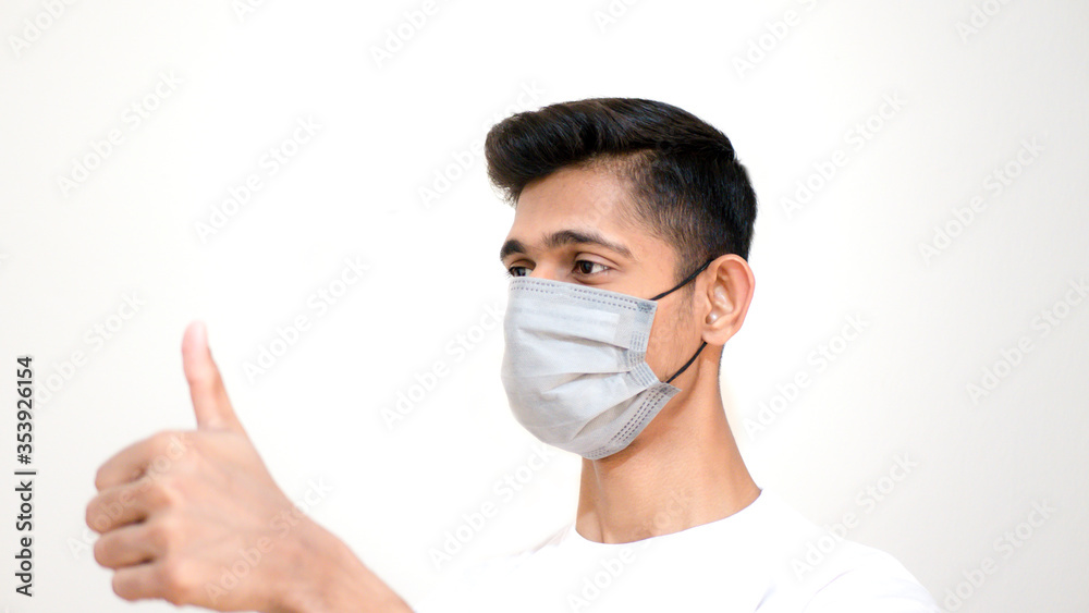 Young Asian boy thumbs up and wearing protective mask against the corona virus covid 19 brown man wearing surgical mask to prevent from virus white background Corona virus pandemic Young Asian boy thumbs up and wearing protective mask against the corona virus covid 19 brown man wearing surgical mask to prevent from virus white background Corona virus pandemic