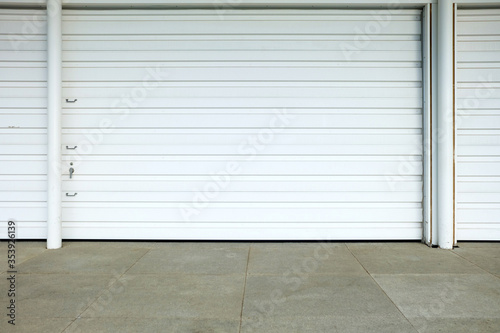 White Folding Metal Door with Concrete Pavement.