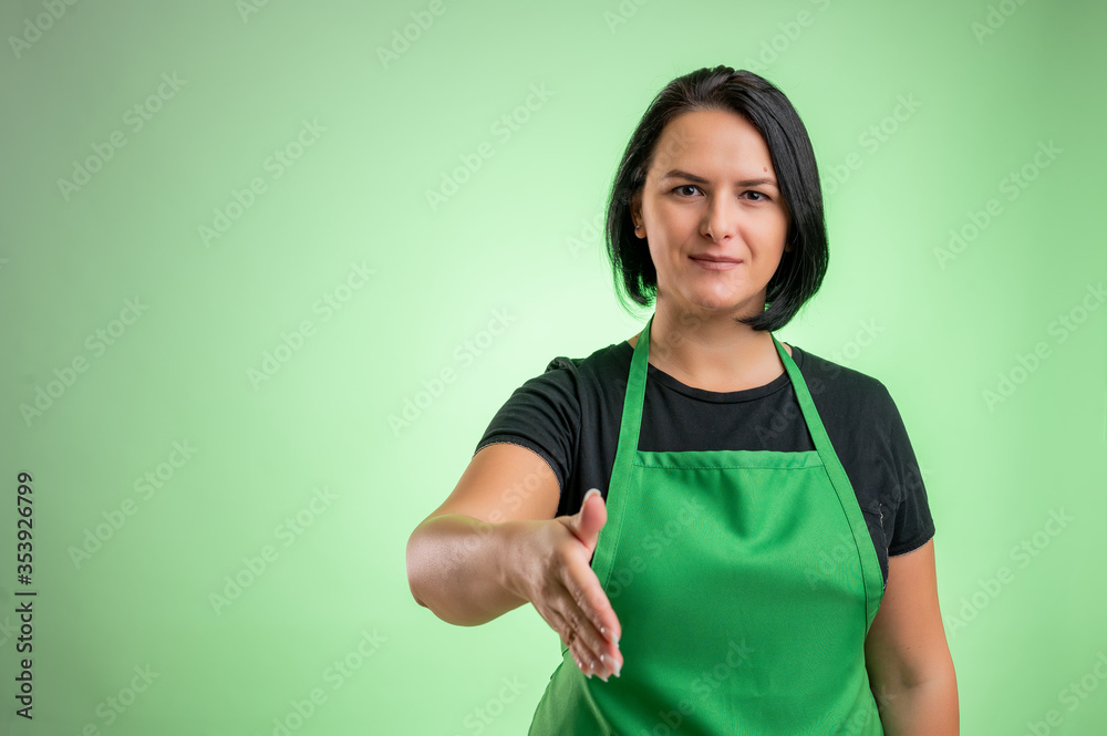Female cook with green apron and black t-shirt shaking hand Female cook with green apron and black t-shirt shaking hand