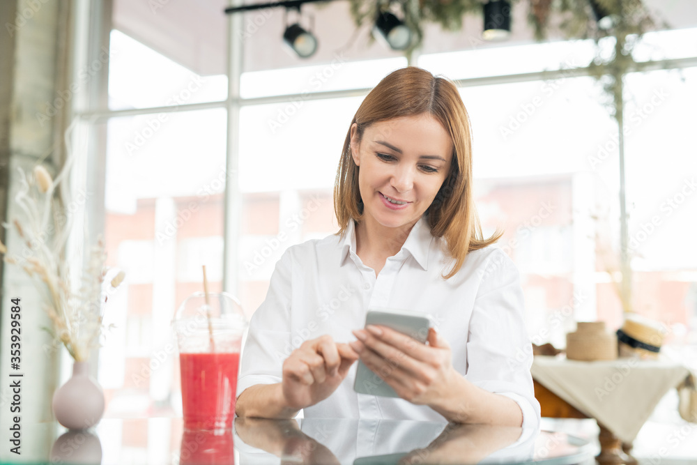 Pretty middle aged woman with smartphone making selfie by drink in cafe Pretty middle aged woman with smartphone making selfie by drink in cafe