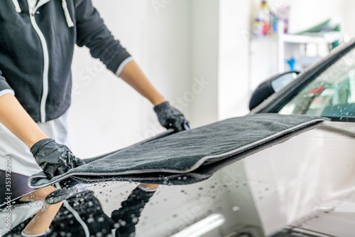 wiping water from the car hood with a microfiber cloth. hand wash luxury cars