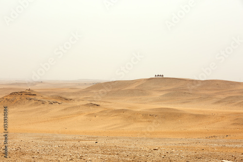 Tourist traveling on camel on the dunes and desert to see the Pyramids of Giza