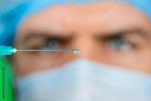 Injection. Doctor with syringe is preparing for injection. Selective focus. Professional doctor with medical syringe in hands ready for injection. Doctor in medical mask holds syringe with vaccine.