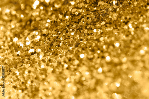 Pile of shining gold pieces seen from above. Top view macro image of sparkling gold dust for backgrounds and textures. Selective focus and shallow depth of field.