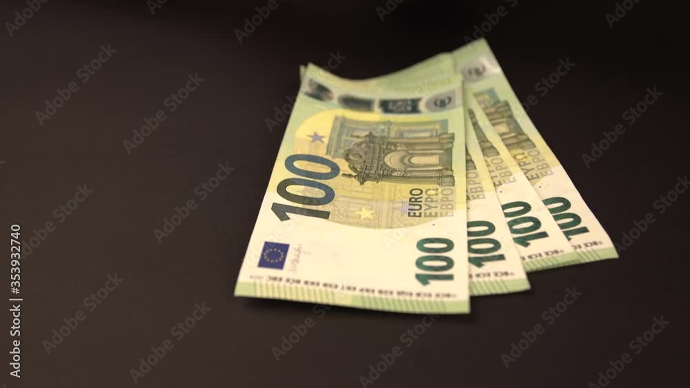 Hands with blue protective medical gloves are counting European 100 (hundred) EURO money banknotes on black background and leave them there. Hands with blue protective medical gloves are counting European 100 (hundred) EURO money banknotes on black background and leave them there.