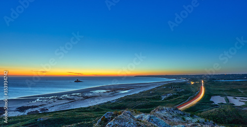 Image of St Ouens Bay in the evening at sunset with car light trails with rocco tower and sand dunes. Jersey, Channel Islands, uk
