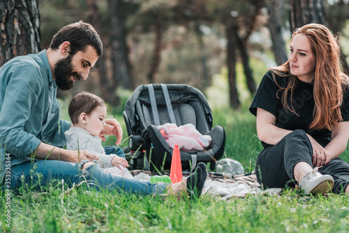 Happy young family with small 8 month daughter having picnic in forest. Cute, Happy, Funny family concept. Father and Mother are playing with daughter and smiling. © A.P Photography