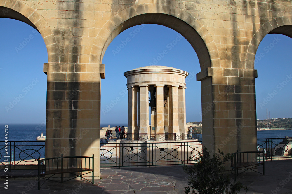 LOWER BARRAKKA GARDENS, VALLETTA, MALTA - NOVEMBER 16TH 2019: The Siege Bell War memorial seen through an archway. Built in 1992 to commemorate the bravery of the Maltese people during World War Two