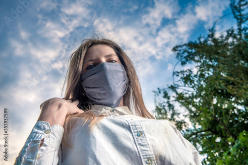 Medical mask, protection against coronavirus and other viruses. Portrait of a woman against a cloudy sky