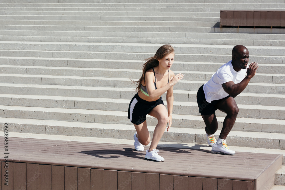 Professional Moroccan athlete coach trains blonde girl outside on the street. Exercises to strengthen the quads Professional Moroccan athlete coach trains blonde girl outside on the street. Exercises to strengthen the quads
