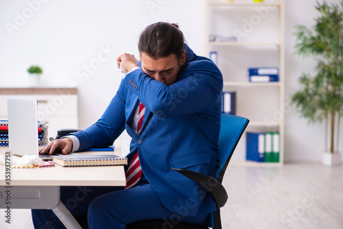 Sick male employee suffering at workplace from coronavirus