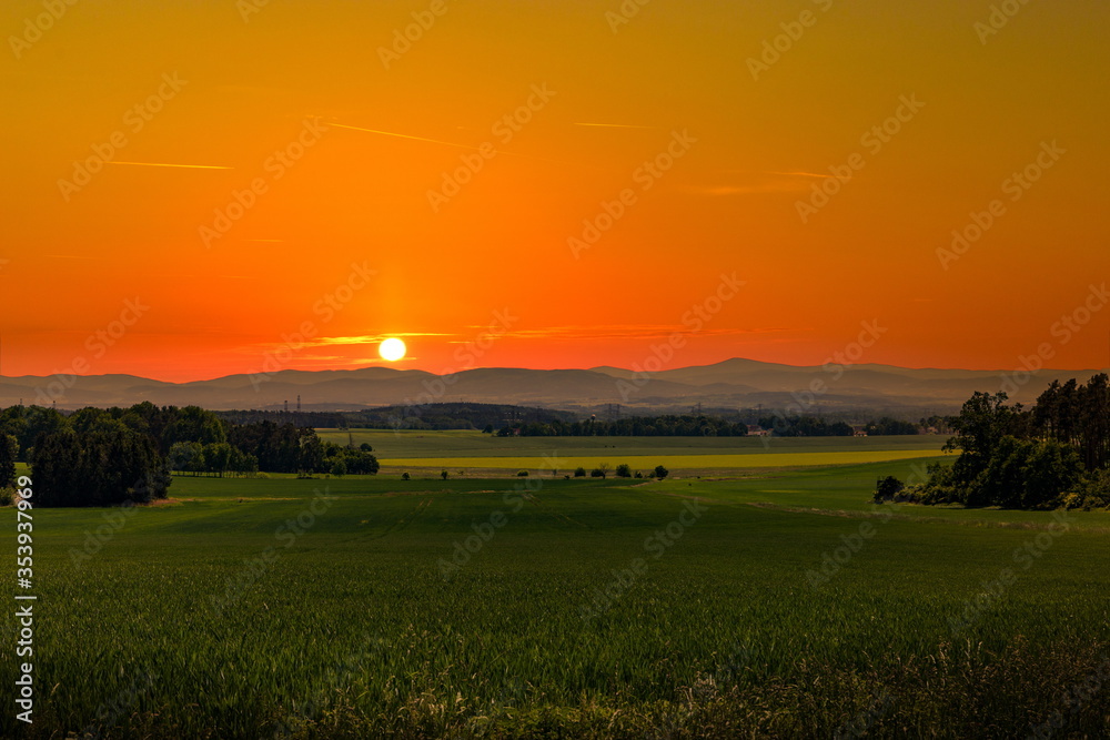 Beautiful sunset over rural field and hills on a horizon.