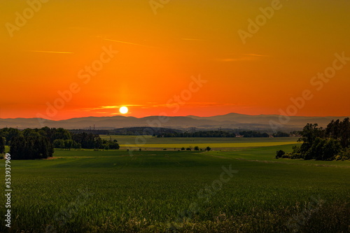 Beautiful sunset over rural field and hills on a horizon.