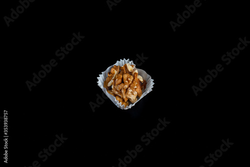 portion of walnuts in a paper muffin cup on a black background