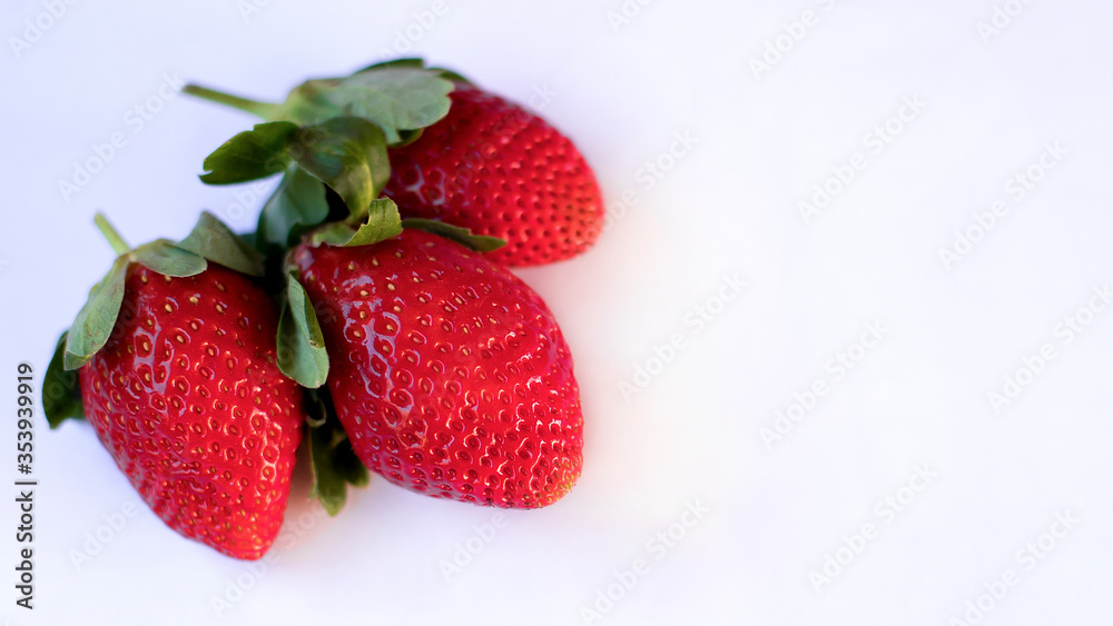 three large ripe fresh strawberries lie on a white background three large ripe fresh strawberries lie on a white background